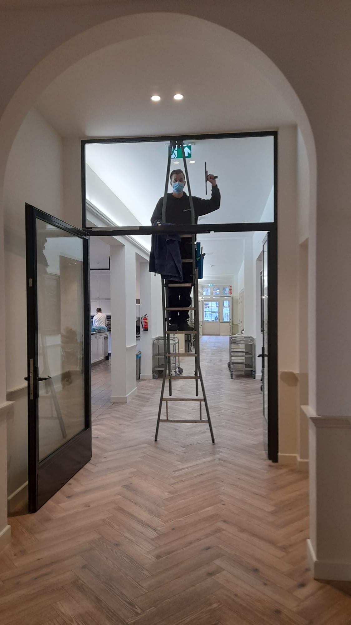 Medewerker reinigt een glazen deur in een zorgvilla